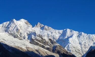Snow-covered peaks of the Himalayan mountains under a clear blue sky.